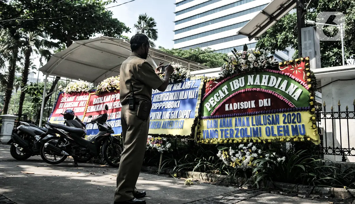 Seorang pegawai mengambil gambar karangan bunga yang terpajang di Balai Kota DKI Jakarta, Senin (6/7/2020). Karangan bunga yang dipasang Relawan PPDB DKI Jakarta 2020 itu sebagai bentuk kekecewaan atas aturan umur serta akreditasi dalam penerimaan siswa baru Jalur Zonasi. (merdeka.com/Iqbal Nugroho)