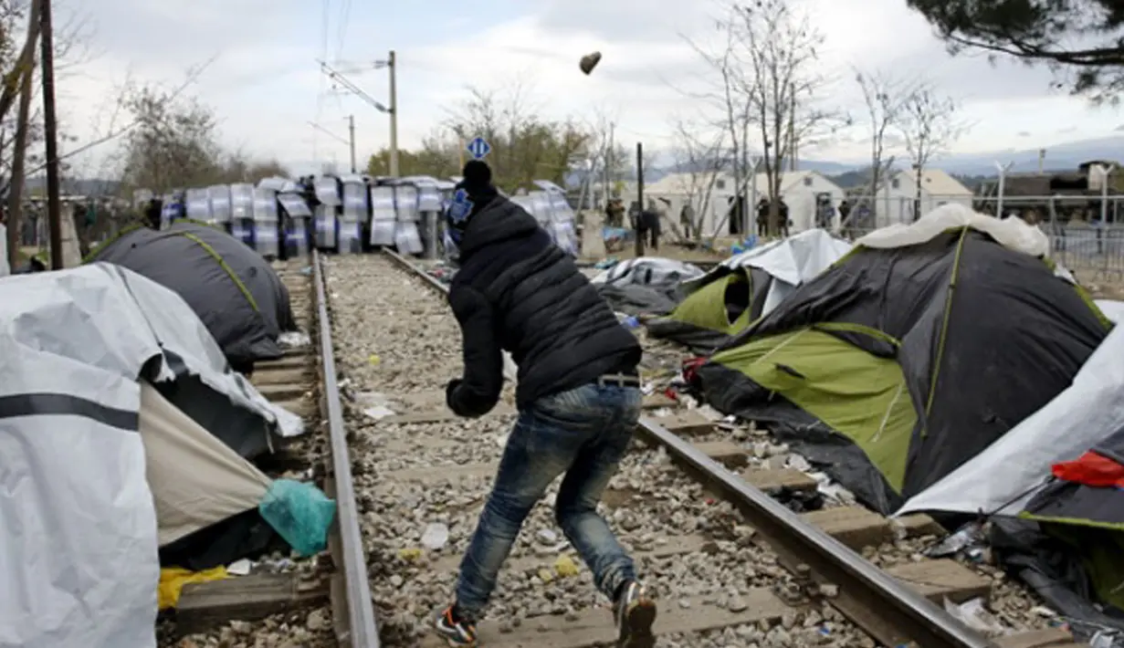 Seorang imigran melempar batu ke arah polisi Makedonia di Desa Idomeni, Yunani (28/11/2015). (REUTERS/Yannis Behrakis)