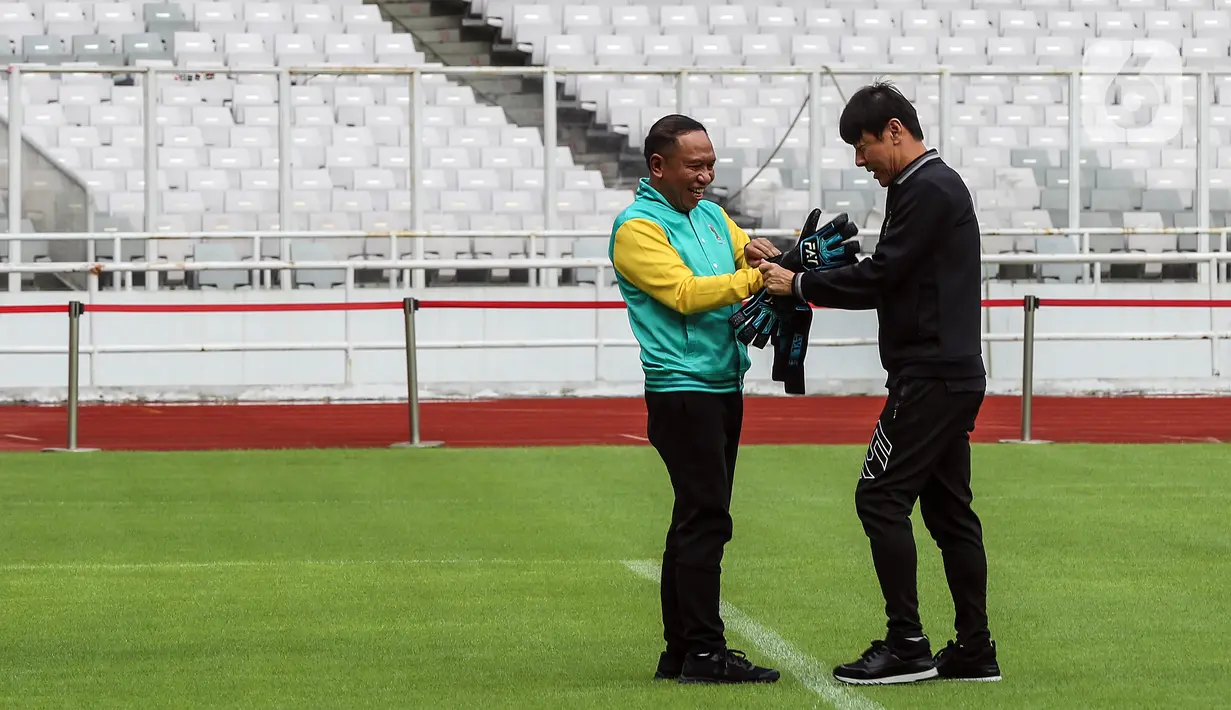 Pelatih Timnas Indonesia Shin Tae-yong (kanan) memasangkan sarung tangan untuk Menteri Pemuda dan Olahraga Zainudin Amali saat Hitung Mundur 100 Hari Menuju Piala Dunia U-20 di Stadion Utama Gelora Bung Karno, Jakarta, Kamis (9/2/2022). Piala Dunia U-20 2023 akan digelar di Indonesia mulai 20 Mei hingga 11 Juni mendatang di Stadion Utama Gelora Bung Karno. (Liputan6.com/Johan Tallo)