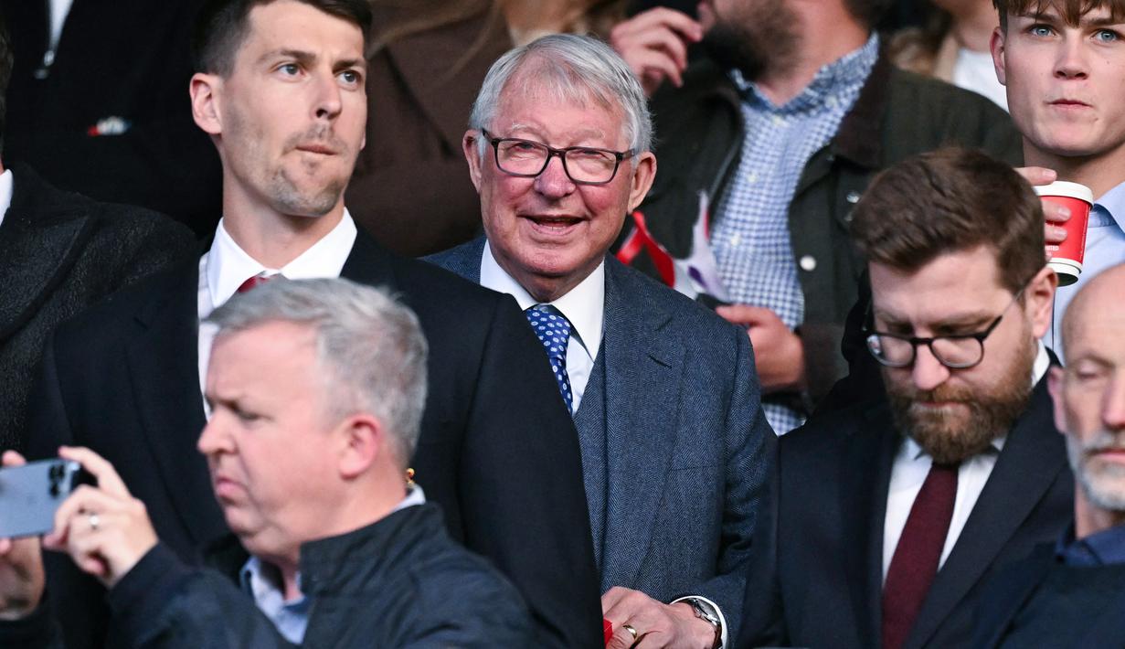 Pelatih legendaris Setan Merah, Sir Alex Ferguson, tampak tersenyum melihat Manchester United sukses melaju ke final Liga Europa 2024/2025 usai mengandaskan Athletic Bilbao dalam laga leg kedua semifinal yang dihelat di Old Trafford, Jumat (9/5/2025) dini hari WIB. (AFP/Oli Scarff)