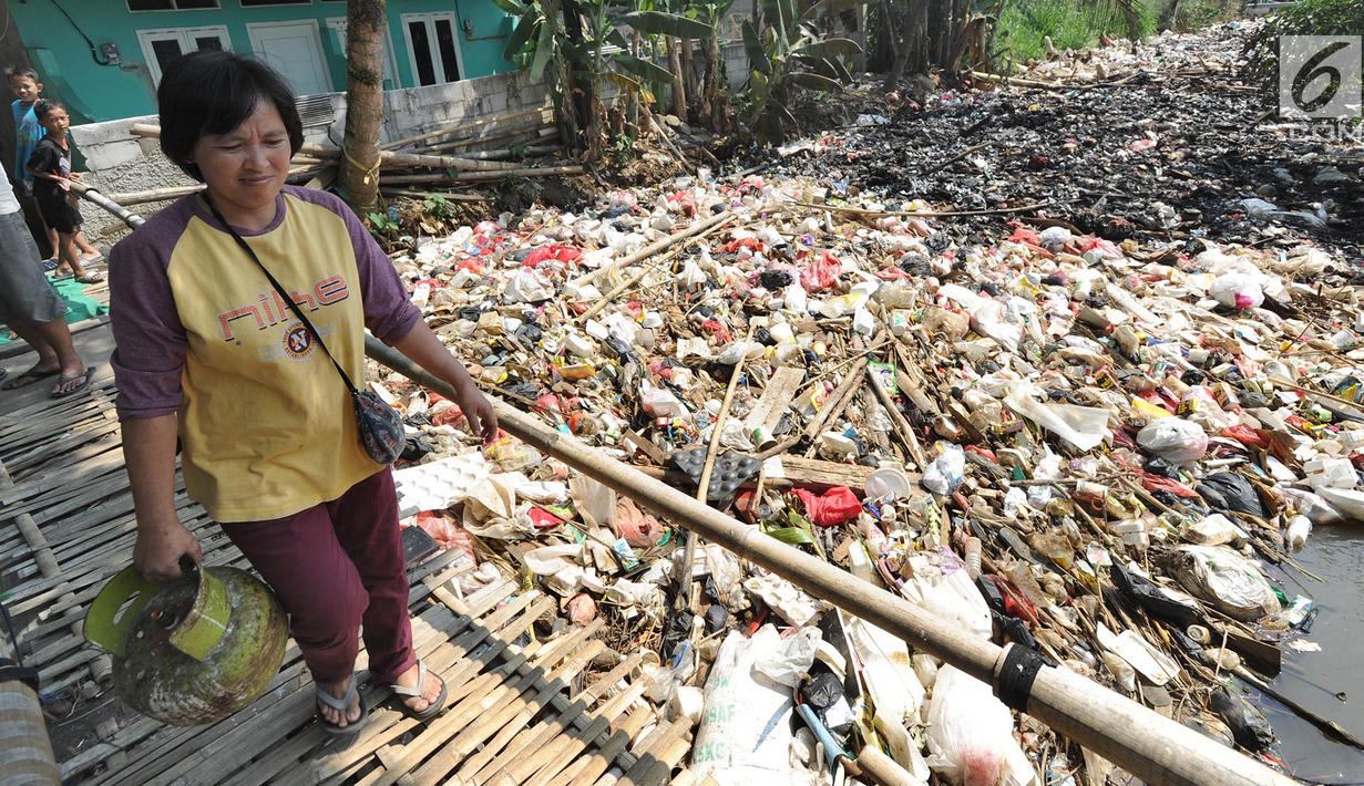 Warga melewati jembatan bambu di atas Sungai Kalibaru yang sudah menjadi tumpukan sampah di Kampung Bambu Kuning, Bojong Baru, Bogor (12/9). (Merdeka.com/Arie Basuki)