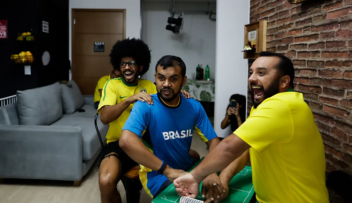 Helio Fonseca (kanan) dan Vinicius Alves (kiri) membantu teman mereka yang tuli dan buta Carlos Junior (tengah) dengan play-by-play pertandingan sepak bola Grup G Piala Dunia antara Brasil dan Swiss, di Osasco, Sao Paulo, Brasil, 28 November 2022. Fonseca dan Alves menggunakan meja taktil dan sentuhan pada tubuh tunanetra dan tunarungu untuk menunjukkan kepada mereka pergerakan bola dan para pemain selama pertandingan sepak bola. (AP Photo/Marcelo Chello)