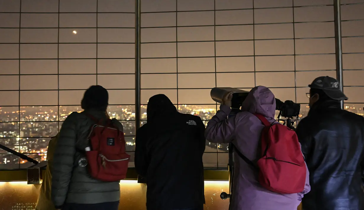 Orang-orang mengambil foto 'Blood Moon' saat gerhana bulan total di Beijing pada 8 November 2022. Fenomena gerhana bulan total terjadi pada 8 November 2022 di berbagai negara.  (AFP/Jade Gao)