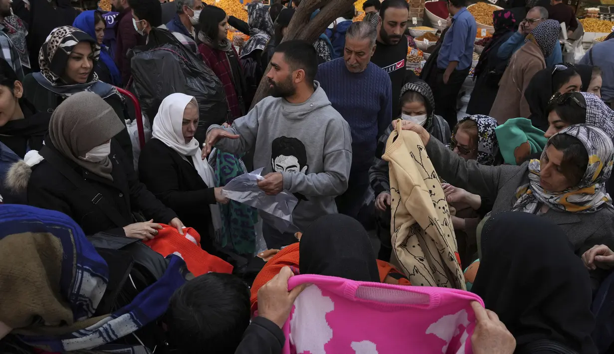 Seorang pedagang kaki lima menjajakan pakaian di bazaar bersejarah tua Teheran, Iran, Minggu (26/2/2023).  Mata uang Iran anjlok hingga rekor terendah akibat berlanjutnya demonstrasi anti pemerintah dan sanksi ekonomi dunia internasional. (AP Photo/Vahid Salemi)
