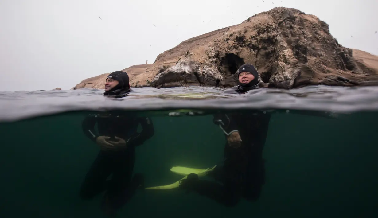 Dua penyelam bersantai setelah menjelajahi lambung kapal yang karam di Pantai Ancon, dekat Lima, Peru, Minggu (27/3). (AP Photo/Rodrigo Abd)