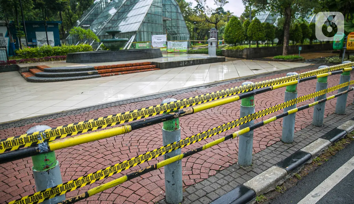 Garis dilarang melintas dipasang di sekitar Taman Menteng, Jakarta, Kamis (31/12/2020). Pemprov DKI Jakarta mulai hari ini menutup sementara seluruh taman dan hutan kota di Ibu Kota jelang Tahun Baru 2021 untuk mengantisipasi penyebaran virus Covi-19. (Liputan6.com/Faizal Fanani)