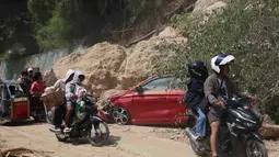 Para pengendara motor melewati lokasi tanah longsor akibat gempa bumi, Provinsi Sarangani, Filipina, Rabu 10 Juni 2026. (AP Photo/Basilio Sepe)