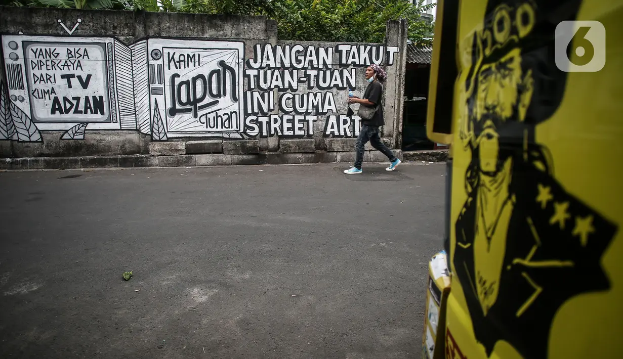 Pejalan kaki melintas di depan mural di kawasan Jakarta Pusat. Selasa (24/8/2021). Menjamurnya mural dan grafiti penuh muatan kritikan merupakan suara para seniman untuk berekspresi di tengah pandemi. (Liputan6.com/Johan Tallo)