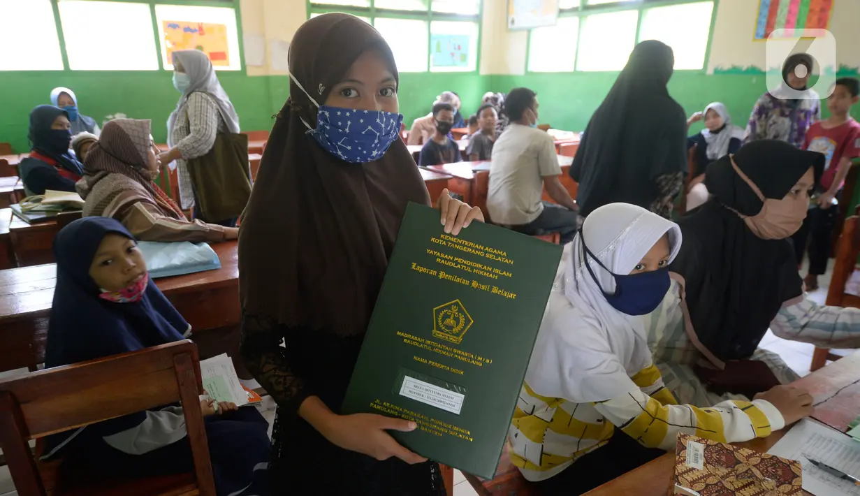 Siswa Sekolah SD kelas 4,5 dan 6 menunjukkan rapot di Sekolah Islam Raudlatul Hikmah, Parakan, Pondok Benda, Pamulang, Tangerang Selatan, Banten, Jumat (16/10/2020). Pengambilan hasil rapot selama belajar mengajar secara online dimasa panemi Covid-19. (merdeka.com/Dwi Narwoko)