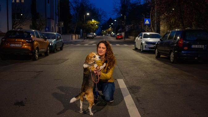 Catalina Gherghel (34) berpose dengan anjingnya Ziggy Stardust  (7) di Bucharest (29/3/2020). Undang-undang militer, yang disahkan pemerintah Rumania untuk mengurangi penyebaran virus corona, menyatakan berjalan bersama anjing adalah salah satu  kegiatan yang masih diizinkan. (AFP/Andrei Pungovschi)