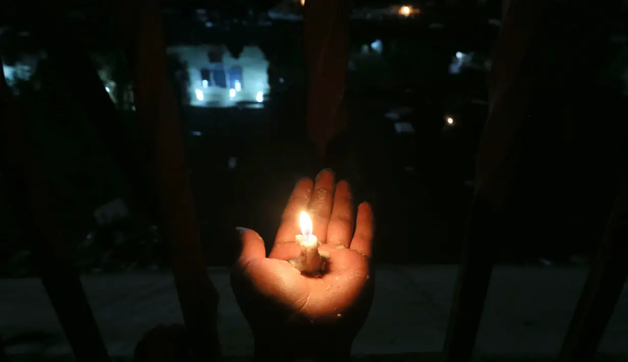 Seorang peziarah memegang lilin di luar kuil Imam al-Mahdi selama upacara Shaabaniya memperingati kelahiran Imam di kota Karbala, Irak tengah, (2/5). Peringatan ini datang dua minggu sebelum dimulainya bulan suci Ramadan. (AFP Photo/Mohammad Sawaf)