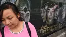 Seorang wanita menunggu di depan poster film Asura di stasiun kereta bawah tanah di Beijing, Selasa (17/7). Meski digadang-gadang sebagai film termahal di China, namun faktanya Asura tak berkutik di box office. (AFP/GREG BAKER)