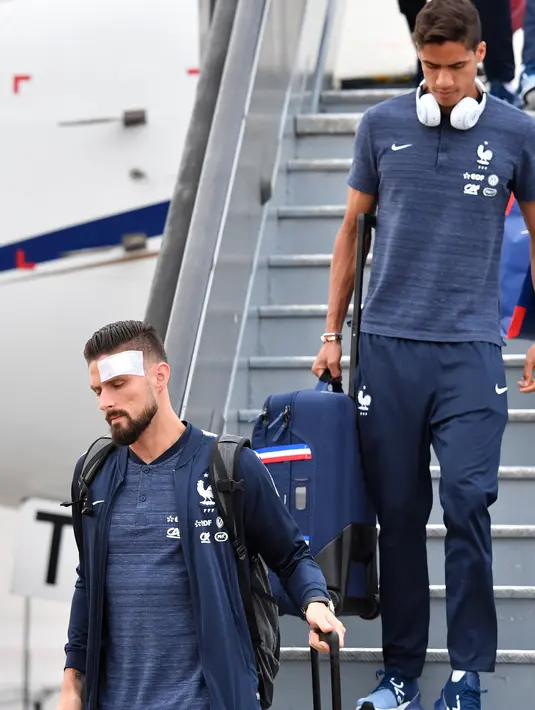Penyerang Timnas Prancis,  Olivier Giroud dan rekan setimnya turun dari pesawat setibanya di bandara Sheremetyevo Moskow, Minggu (10/6). Giroud ikut dalam rombongan yang akan berlaga di Piala Dunia 2018 meski sedang kondisi cedera. (AP/Pavel Golovkin)
