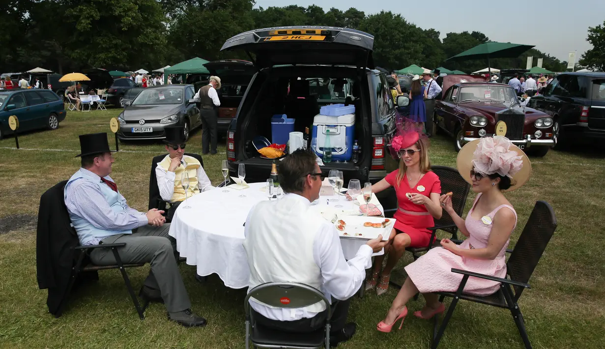 Dua wanita berbincang dengan rekannya saat makan siang di tempat parkir menjelang balap kuda di Ascot, London, (20/6). Balap kuda ini telah diadakan di Berkshire sejak tahun 1711. (AFP Photo/Daniel Leal-Olivas)