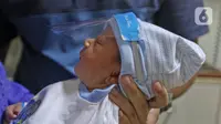 Seorang bayi memakai face shield atau pelindung wajah di Rumah Sakit Ibu dan Anak Tambak, Jakarta, Selasa (14/4/2020). RSIA Tambak sejak 12 April 2020 membuat kebijakan bayi yang baru lahir dipakaikan pelindung wajah untuk mencegah terpapar virus corona COVID-19. (Liputan6.com/Herman Zakharia)