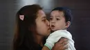 Sambil mencium anaknya, Enry Khairul terus menunggu kabar suaminya, Mohd Khairul Amri Selamat yang menjadi penumpang Malaysia Airlines MH370 (REUTERS/Samsul Said)