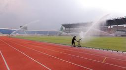 Seorang pekerja menyiram rumput Stadion Si Jalak Harupat (SJH), Bandung, Sabtu (21/10/2023). (Bola.com/Bagaskara Lazuardi)