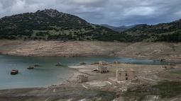 Foto ini menunjukkan sisa-sisa rumah yang muncul kembali ketika permukaan danau buatan Mornos menurun akibat kekeringan, di desa Kallio, sekitar 240 km barat laut Athena, Yunani pada 3 November 2025. Ketinggian air di danau yang terletak sekitar 240 km barat laut Athena anjlok ke titik terendah dalam 15 tahun terakhir. (Angelos TZORTZINIS/AFP)