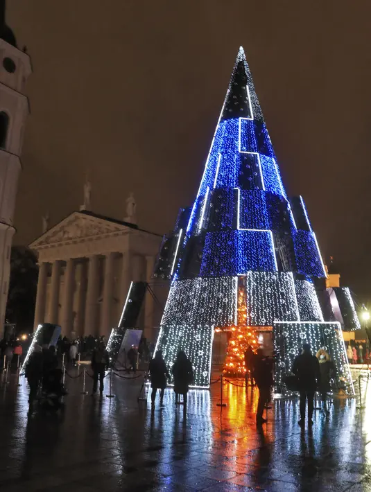 Pohon Natal yang menyala terlihat di dekat katedral di Vilnius, Lithuania pada 28 November 2020. Pohon natal raksasa yang dihiasi berbagai ornamen lampu hias tersebut membuat kawasan di ibu kota Lithuania menjadi terang. (PETRAS MALUKAS / AFP)