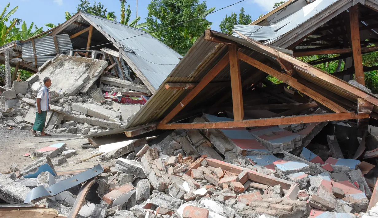 Warga memeriksa bangunan rumah yang roboh akibat gempa yang melanda Lombok, NTB, Minggu (29/7). Data sementara BPBD Provinsi NTB mencatat, gempa bumi tektonik 6.4 SR itu mengakibatkan 10 orang meninggal dunia dan puluhan rumah rusak. (AFP/Aulia AHMAD)