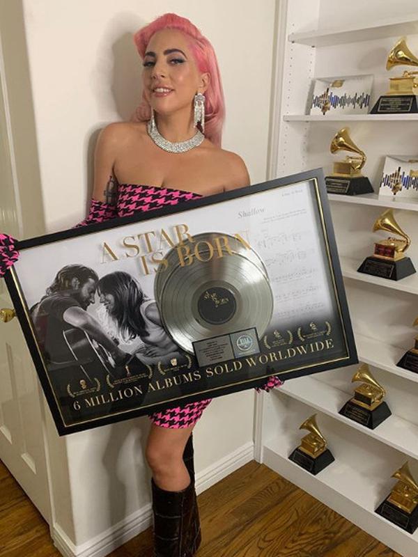 Lady Gaga dengan Pose di depan rak sambil memegang plakat penghargaan penjualan lagunya (dok Instagram @ladygaga/https://www.instagram.com/p/B3Pn43iFsm0/Ossid Duha Jussas Salma)