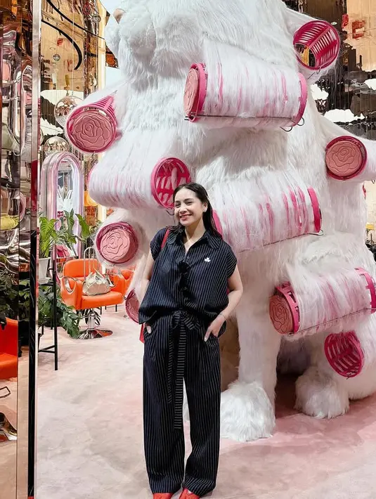 Nagita Slavina memilih liburan ke Bangkok seorang diri tanpa keluarga. Ia terlihat mengenakan setelan warna hitam bergaris dipadukan flat shoes merah menyala. [@raffinagita1717]