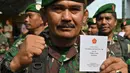 Seorang tentara menunjukkan buku pedoman netralitas untuk anggota militer saat apel pengamanan Pemilu 2019 di Bogor, Jawa Barat, Rabu (10/4). TNI-Polri menyatakan siap mengamankan masyarakat sampai ke TPS hingga pesta demokrasi selesai. (ADEK BERRY/AFP)