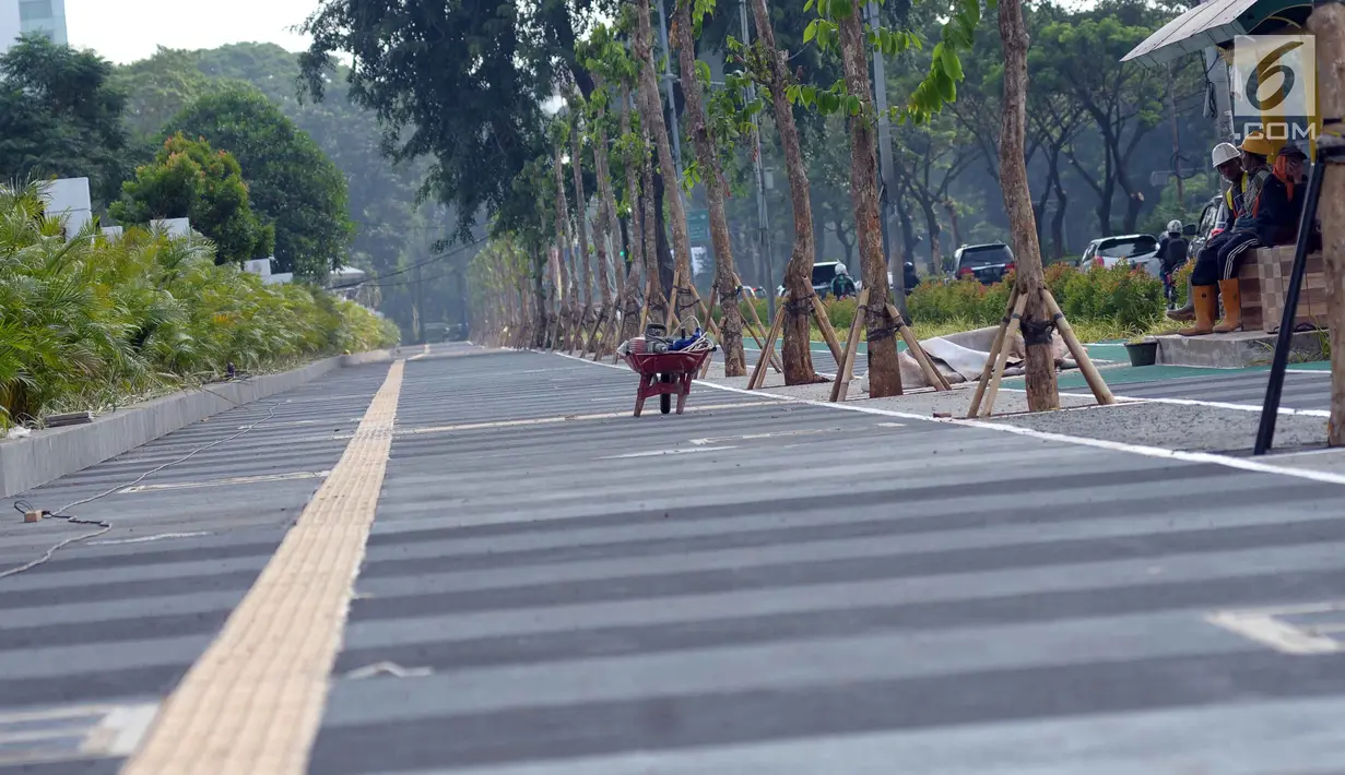 Sejumlah pekerja beristirahat disela-sela pengerjaan tahap akhir renovasi trotoar di sekitar Jalan Gerbang Pemuda, Senayan, Jakarta, Selasa (29/5). Renovasi sebagai bagian persiapan pelaksanaan Asian Games 2018. (Liputan6.com/Helmi Fithriansyah)