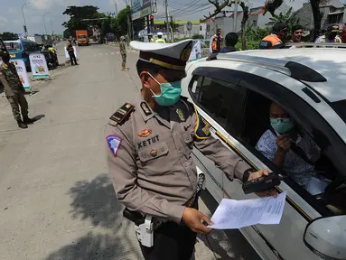 Polantas Polres Bogor memeriksa surat domisili pengemudi mobil  yang melintasi Pos Pengawasan Larangan Mudik di Cigombong, Bogor, Rabu (29/4/2020). Polres Bogor terus melakukan penyekatan  mencegat pemudik sekaligus PSBB mengantsipasi penyebaran virus Covid-19. (merdeka.com/Arie Basuki)