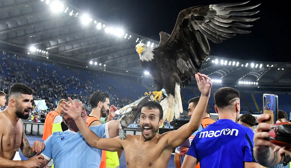 Tak mau ketinggalan, mantan pemain AS Roma yang kini berseragam Lazio yakni Pedro pun ikut merayakan kemenangan bersama burung Elang di depan para pendukung Biancocelesti yang bersorak. (AFP/Vincenzo Pinto)