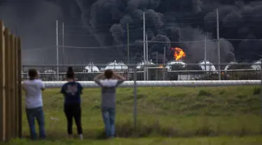 Warga mengamati kebakaran pabrik TPC Group yang meledak di Port Neches, Texas (27/11/2019). Dua ledakan besar 13 jam terpisah membakar pabrik kimia dan menyebabkan tiga pekerja terluka. (Marie D. De Jesús/Houston Chronicle via AP)