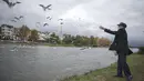 Seorang pria memberi makan kawanan burung yang bermigrasi di tepi sebuah sungai di Tonekabon, Iran utara, pada 30 November 2020. (Xinhua/Ahmad Halabisaz)