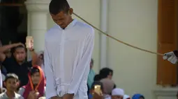 Petugas syariah mencambuk salah satu pasangan gay di depan Masjid Baiturrahim, Aceh (13/7). Nyakrab dan Rustam divonis hukuman cambuk sebanyak 90 kali, saat eksekusi cambukan dipotong menjadi 87 kali karena pengurangan masa tahanan. (AP Photo/Heri Juanda)