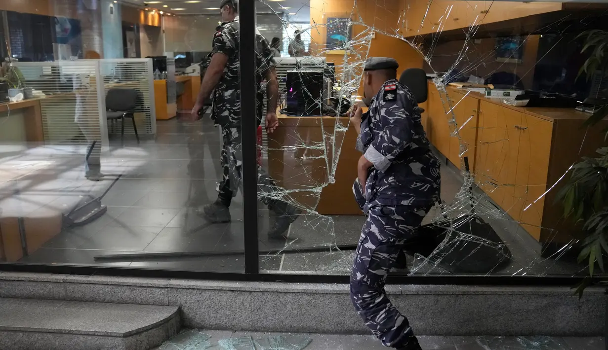 Polisi Lebanon memasuki bank dari jendela yang dirusak oleh para deposan untuk keluar dari bank setelah mencoba mengambil uang mereka, Beirut, Lebanon, Rabu (14/9/2022). Semenjak krisis ini terjadi di Lebanon muncul kasus perampokan bank. (AP Photo/Hussein Malla)