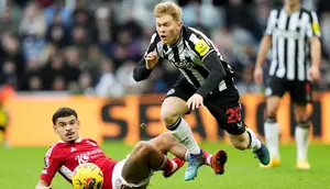 Pemain Newcastle United, Lewis Hall, terjatuh saat berebut bola dengan pemain Nottingham Forest, Morgan Gibbs-White, dalam lanjutan Liga Inggris di St James Park, Selasa (26/12/2023). (AFP/Andu Buchanan)
