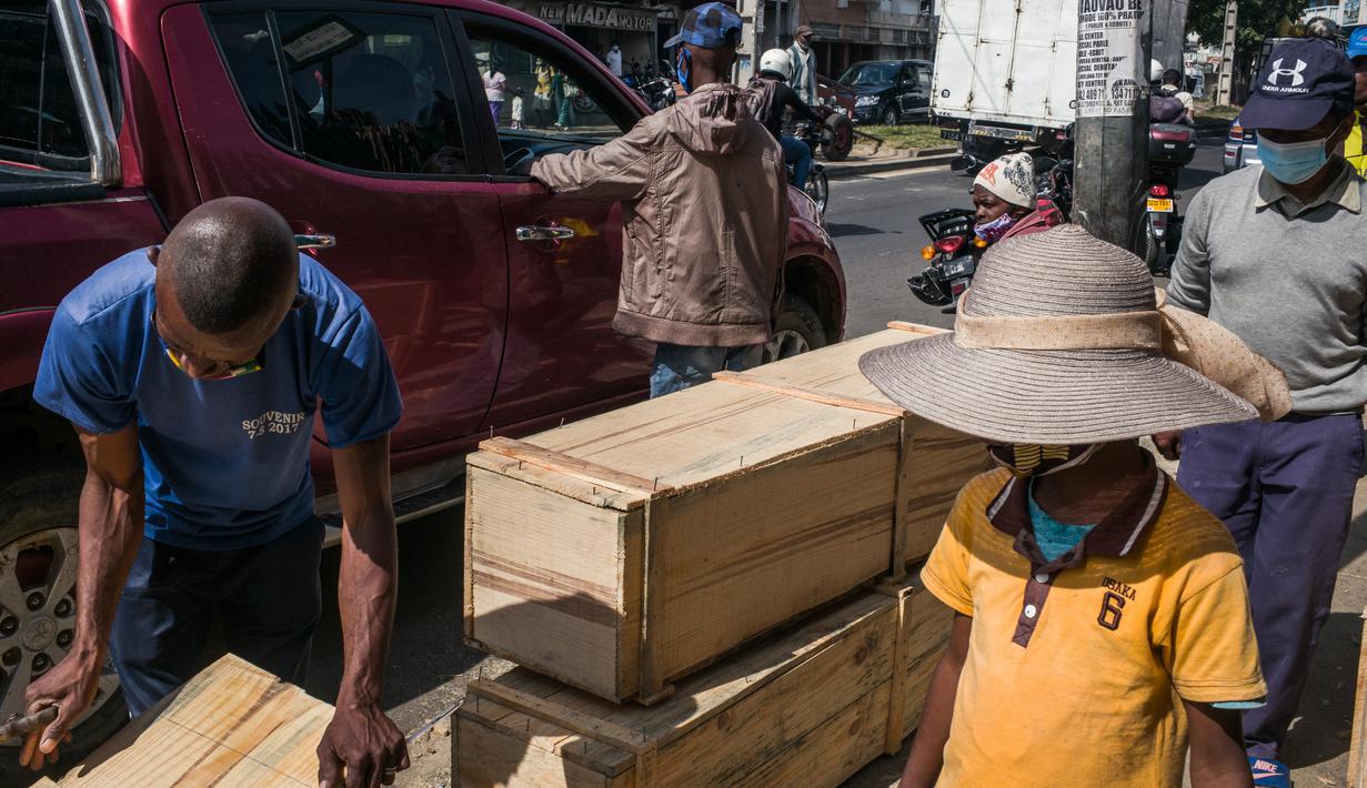 Sebuah mobil berhenti untuk memesan peti mati dari Mr. Jean dan timnya di jalan di Antananarivo, Madagaskar, Rabu (14/4/2021). Selama tiga minggu terakhir, Pak Jean dan timnya memproduksi antara 15 hingga 20 peti mati per hari, padahal sebelumnya hanya 3 atau 4 peti mati per hari. (RIJASOLO/AFP)