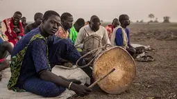 Penggembala dari suku Dinka bermain alat musik di kamp ternak mereka di Mingkaman, Lakes State, Sudan Selatan, Minggu (4/3). Mereka akan mendirikan kamp ternak besar untuk memastikan hewan mereka dekat dengan air. (Stefanie GLINSKI/AFP)