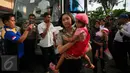 Seorang Polwan menggendong salah satu anak eks anggota Gafatar yang tiba di Penampungan Youth Center, Sleman, Yogyakarta, Jumat (29/1). Mereka sebelumnya ditampung di wisma Haji Donohudan, Boyolali untuk pendataan kependudukan (Foto: Boy Harjanto)