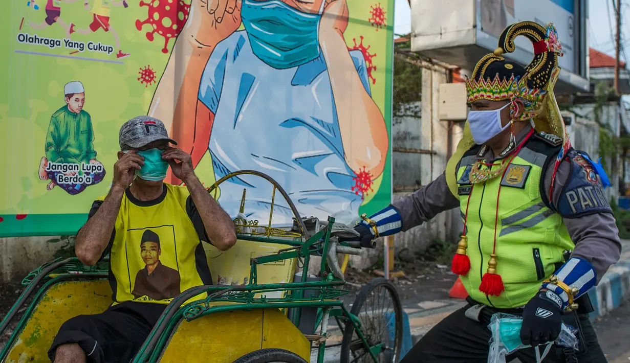 Petugas kepolisian berpakaian superhero memberikan masker kepada warga di jalan kawasan Pasuruan, Jawa Timur, Kamis (9/4/2020). Hal tersebut bertujuan untuk mengantisipasi penyebaran Virus Corona (COVID-19). (JUNI KRISWANTO / AFP)