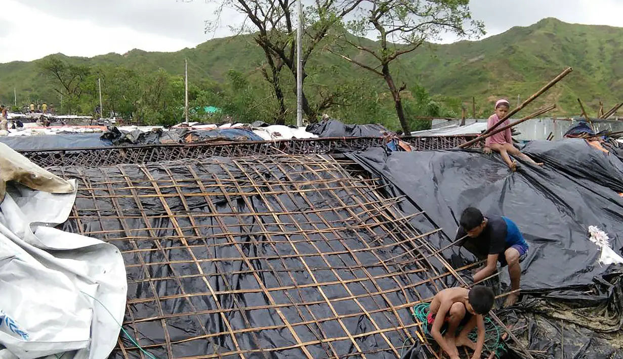Anak-anak pengungsi Rohingya memperbaiki atap gubuk yang rusak di sebuah kamp darurat di distrik Cox's Bazar di Bangladesh (30/5). Akibat bencana tersebut sekitar 300 orang terpaksa dievakuasi. (AFP Photo/Str)