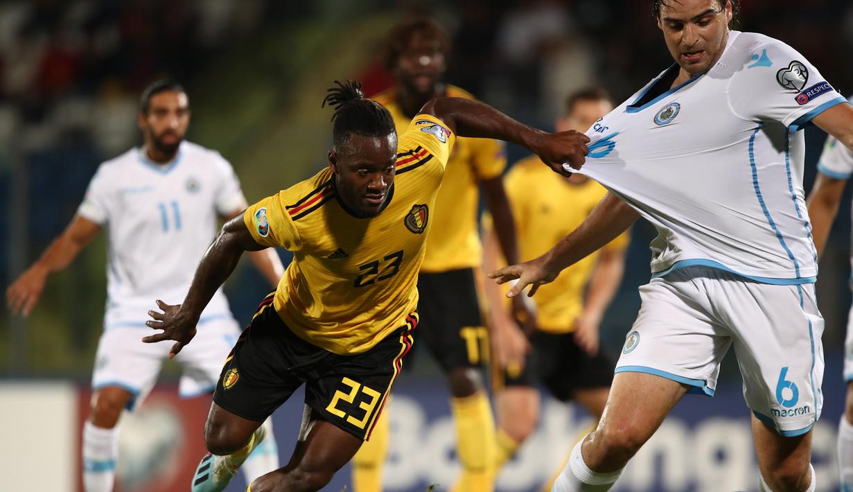 Striker Belgia, Michy Batshuayi, berebut bola dengan bek San Marino, Davide Simoncini, pada laga Kualifikasi Piala Dunia 2022 di Olympic Stadium, Serravalle, Jumat (6/9). San Marino kalah 0-4 dari Belgia. (AFP/Isabella Bonotto)