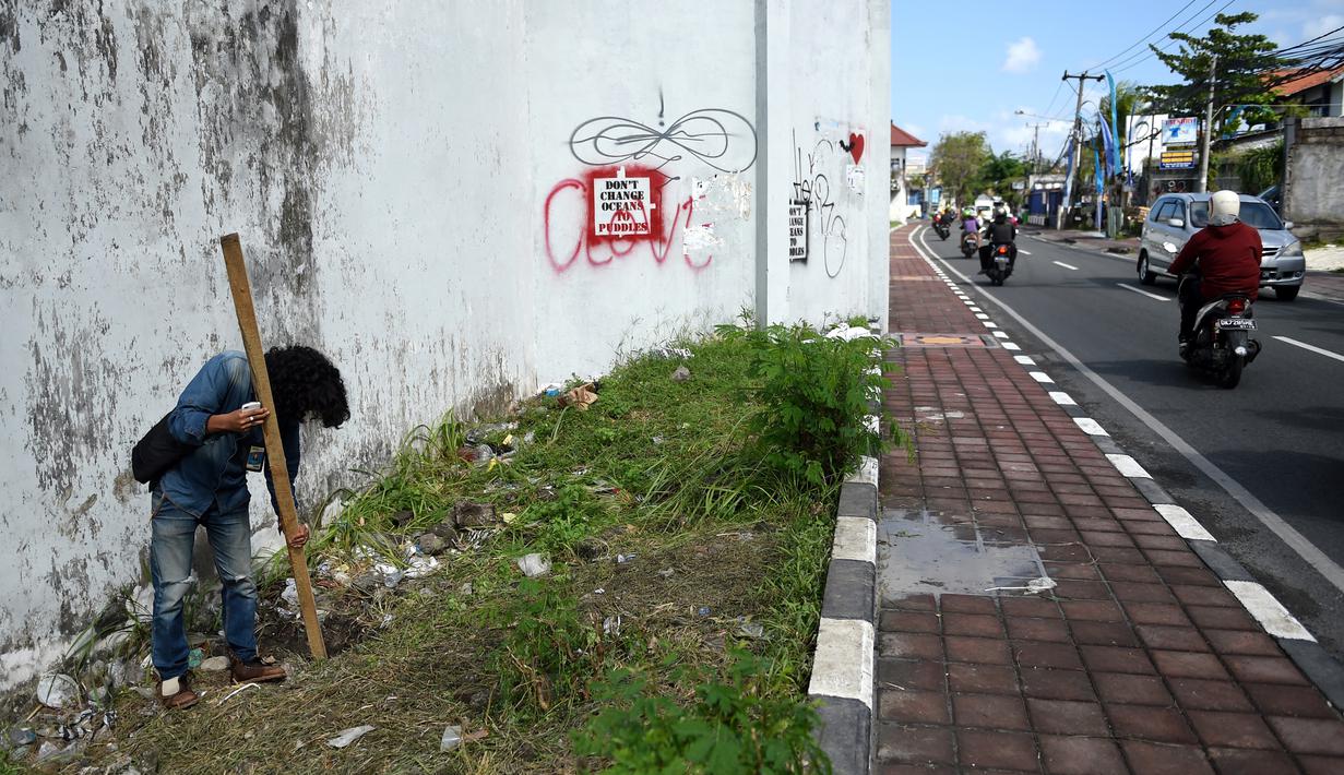 Seorang jurnalis memeriksa lubang yang digunakan narapidana asing untuk kabur dari Lapas Kerobokan, Bali, Senin (19/6). Empat narapidana asing kabur masih diburu petugas setelah meloloskan diri dari lapas melalui terowongan tersebut. (SONNY TUMBELAKA/AFP)