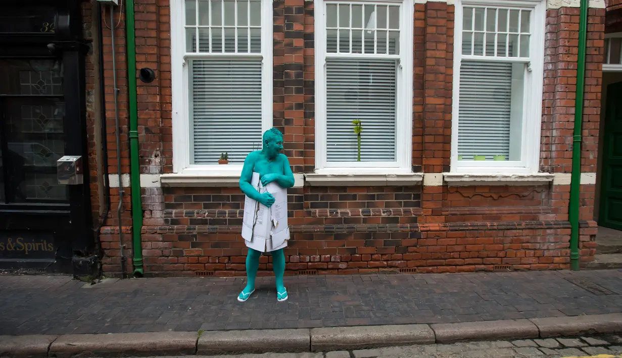 Seorang model memakai kardus menutupi tubuhnya usai mengikuti sesi foto menjadi model sebuah seni berjudul "Sea of Hull" karya Spencer Tunick asal Amerika Serikat di pusat Kota Hull, Inggris, Sabtu (9/7). (AFP Photo/Jon Super)