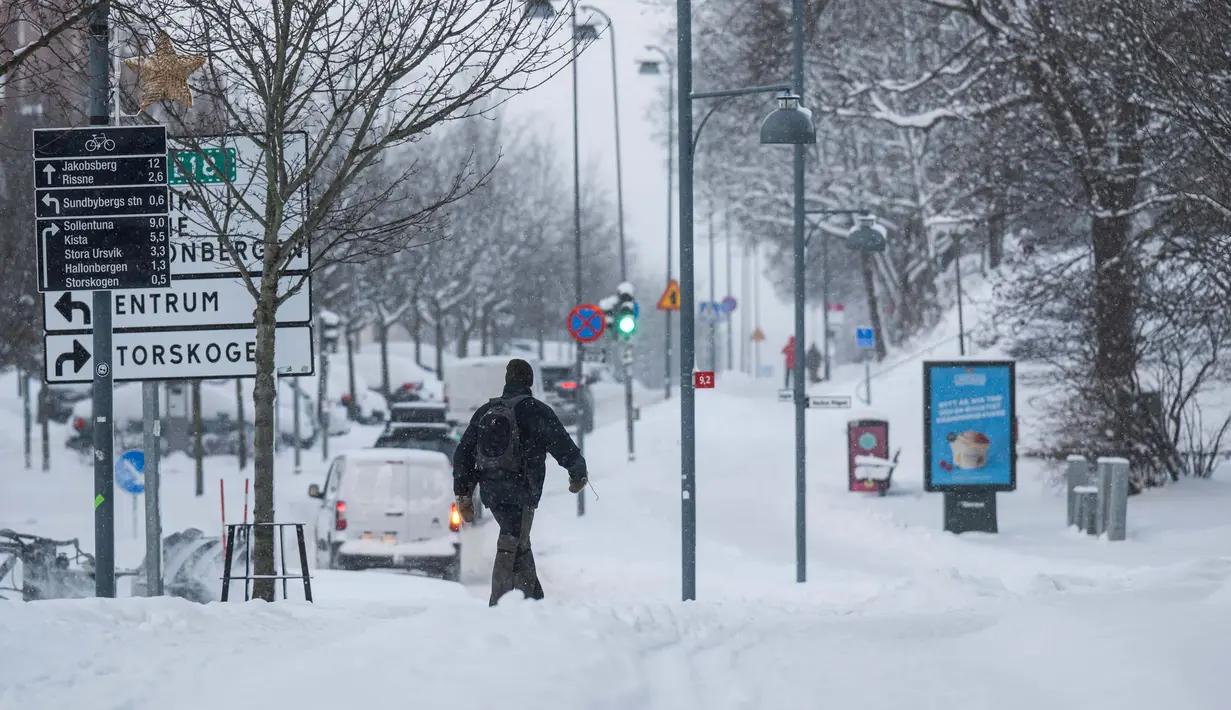 Seorang pria berjalan setelah hujan salju pada tanggal 4 Januari 2024 di Sundbyberg, dekat Stockholm, Swedia. (Jonathan NACKSTRAND/AFP)