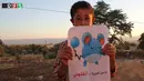 Seorang bocah memegang kertas bergambarkan karakter Pokemon serta tulisan "Aku berasal dari Kafr Zita, tolong selamatkan aku!" Suriah (22/7). (REUTERS)