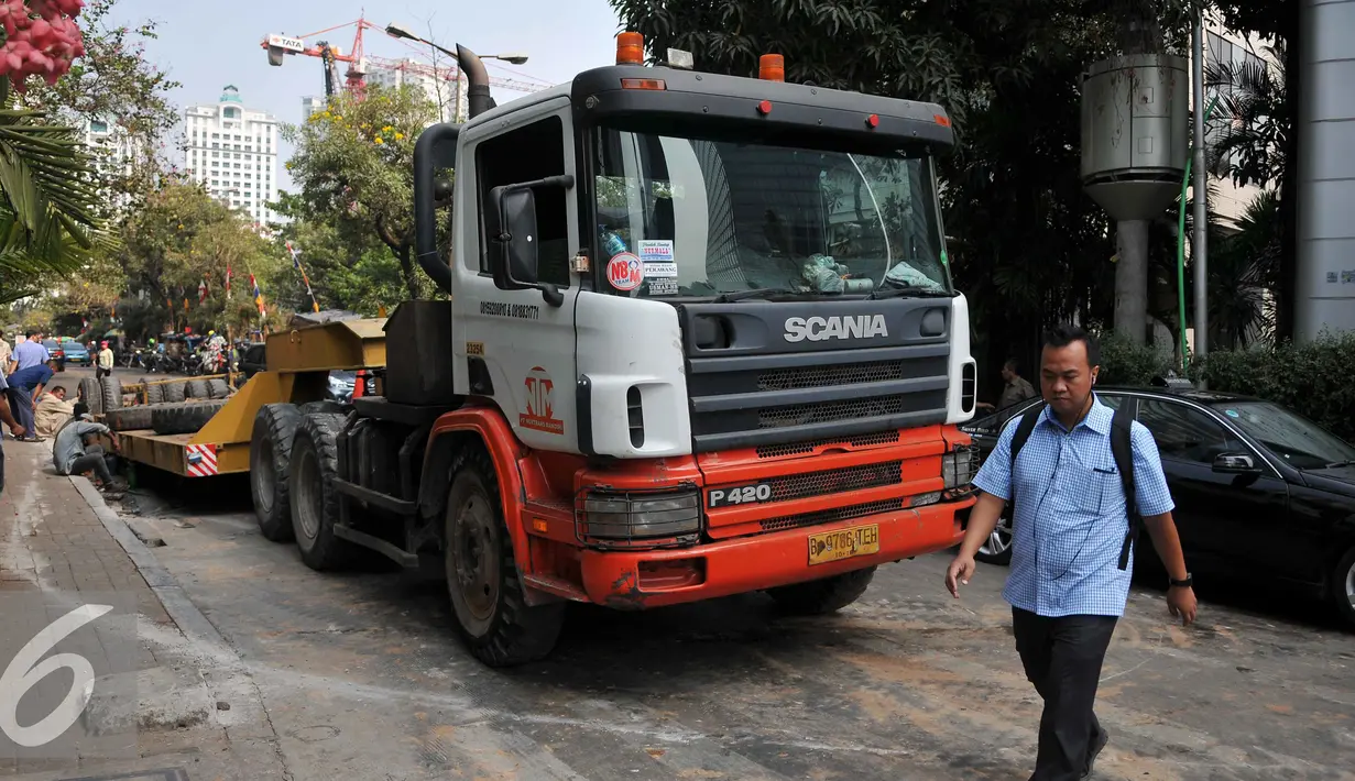 Warga melintas di depan truk yang mengalami patah as di Jakarta, Selasa (29/9/2015). Imbas dari truk bermuatan alat berat mengalami patah as itu, Jalan Sudirman mengarah ke Jalan MH Thamrin terpantau padat. (Liputan6.com/Gempur M Surya)