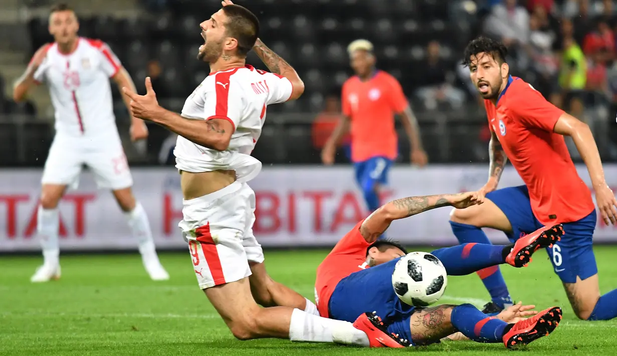 Pemain Serbia, Aleksandar Mitrovic (kiri) jatuh saat berebut bola dengan pemain Chili, Erick Pulgar pada laga uji coba di Merkur Arena, Graz, Austria, (4/6/2018).  Serbia kalah dari Chili 0-1. (AFP/Joe Klamar)
