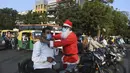 Pengguna jalan dipakaikan masker oleh presiden Angel Foundation dan pekerja sosial, Rufas Christian yang berpakaian Sinterklas di persimpangan lalu lintas di Ahmedabad, India, Kamis (17/12/2020). Aksi itu sebagai bagian dari kampanye kesadaran melawan penyebaran COVID-19. (SAM PANTHAKY/AFP)