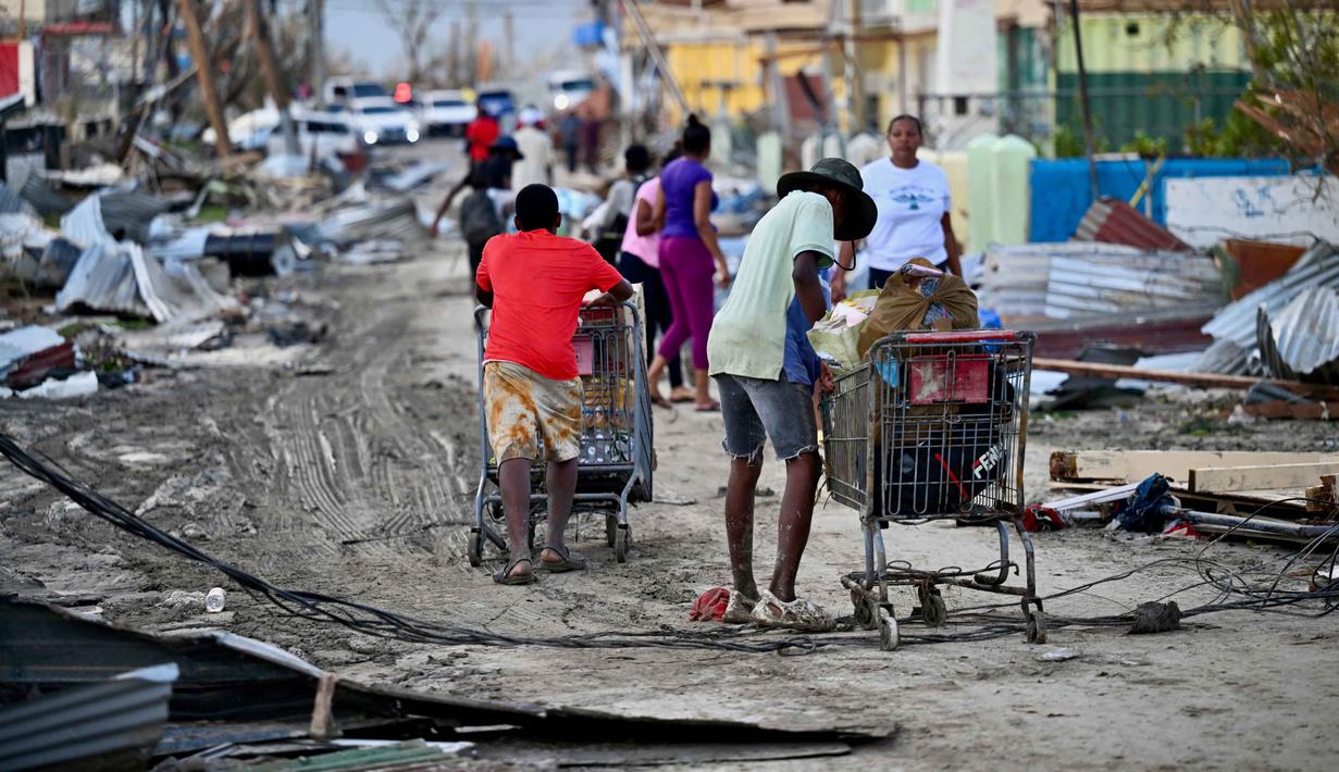 Warga mengais makanan di jalanan Black River setelah Badai Melissa melanda Santa Cruz, St. Elizabeth, Jamaika pada 29 Oktober 2025. Lebih dari setengah juta pelanggan hidup tanpa listrik pada Selasa 28 Oktober 2025 malam waktu setempat akibat pohon tumbang, kabel putus, dan banjir besar yang melanda sebagian besar pulau. Pemerintah Jamaika memprioritaskan pemulihan layanan listrik dan telekomunikasi, serta pembersihan jalan-jalan yang terblokir. (Ricardo MAKYN/AFP)