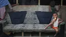 Seorang anak pengungsi Rohingya duduk di sofa yang rusak menikmati es krim di sebuah kamp pengungsi di New Delhi, India (12/9). Pengungsi Rohingya di India diancam pemerintah untuk dideportasi kembali ke Myanmar. (AP Photo/Altaf Qadri)
